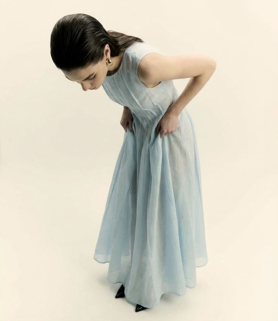 Woman wearing a light blue dress against a beige background