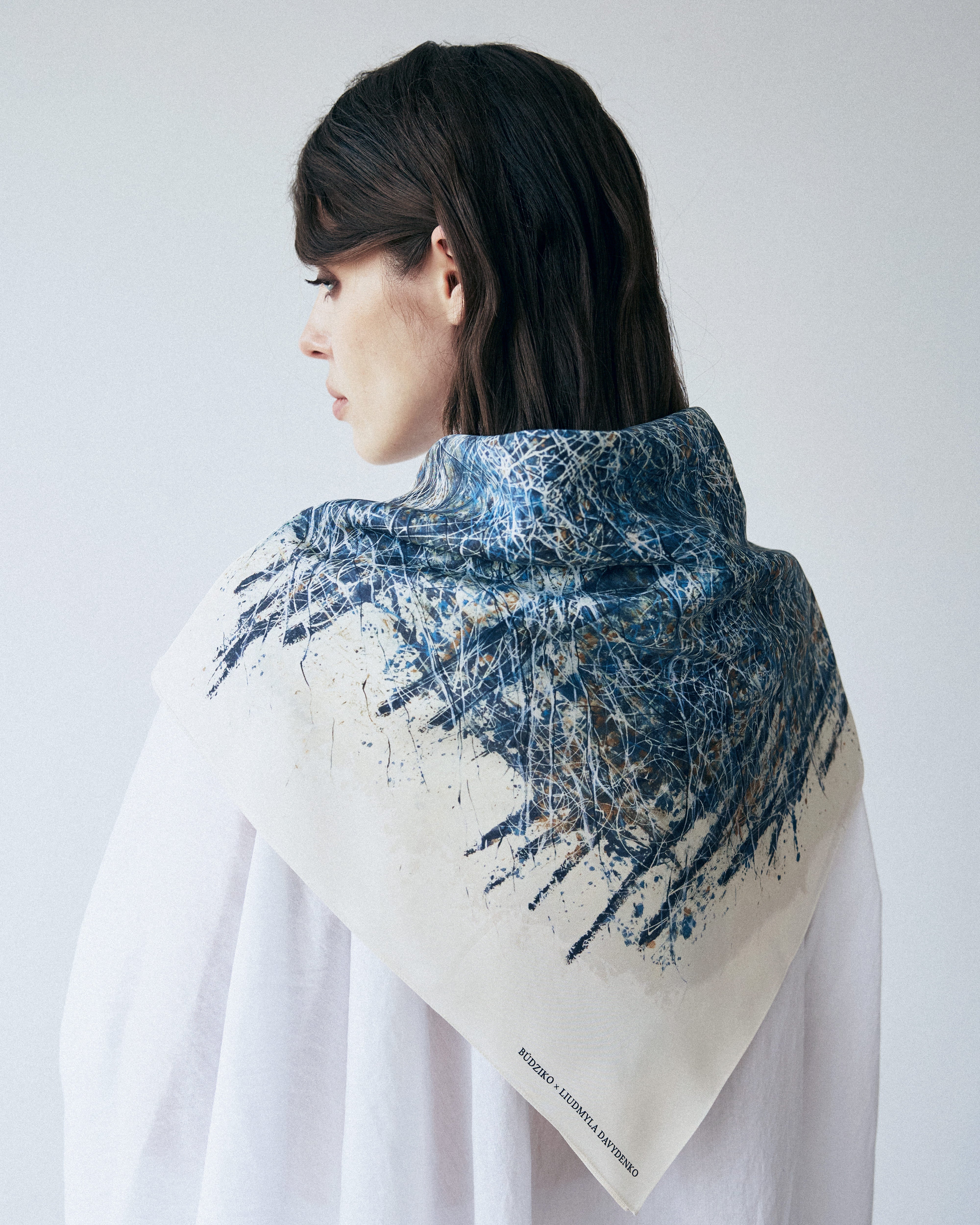 Woman wearing a blue and beige patterned scarf on a white background