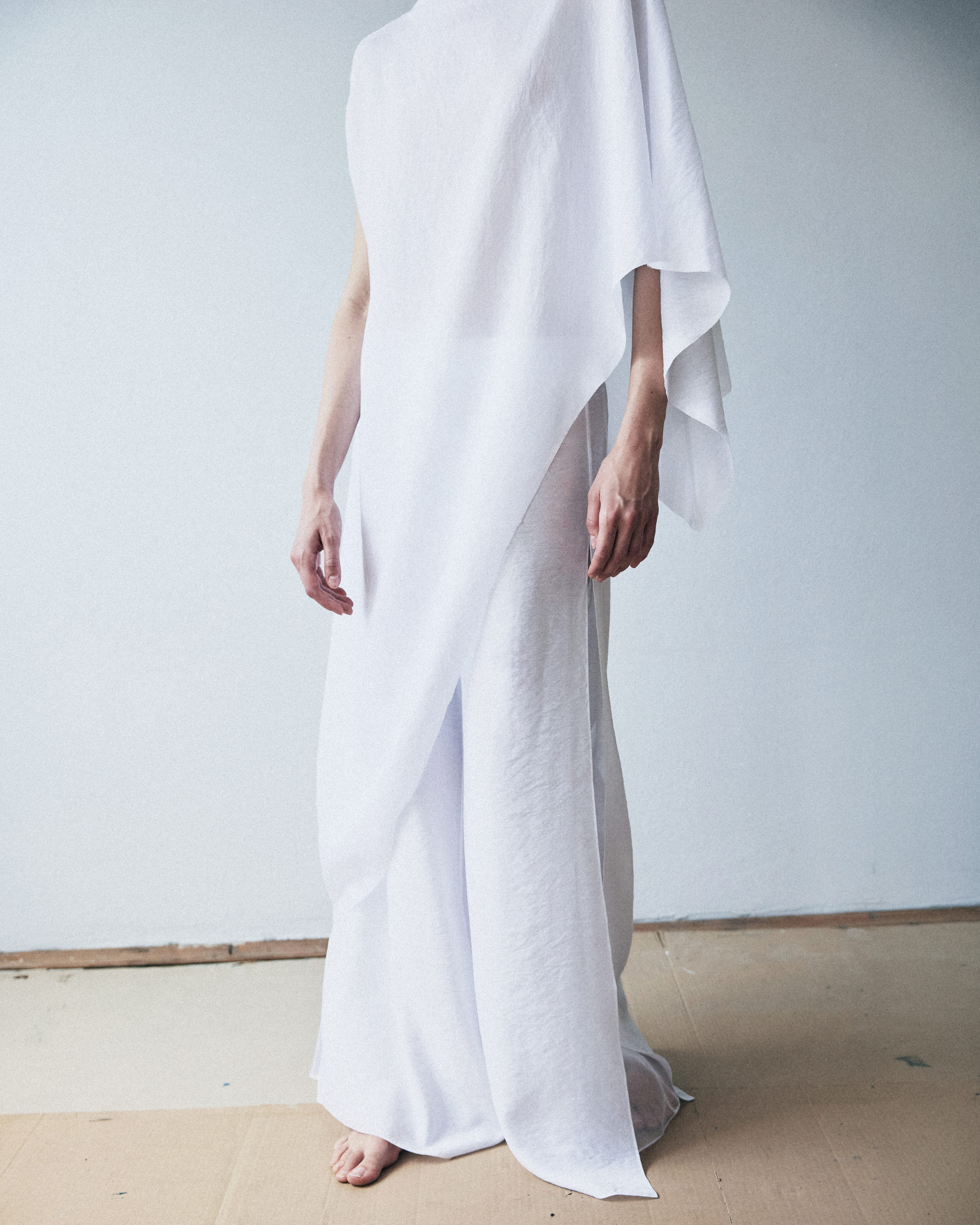 Person wearing a flowing white garment against a plain background