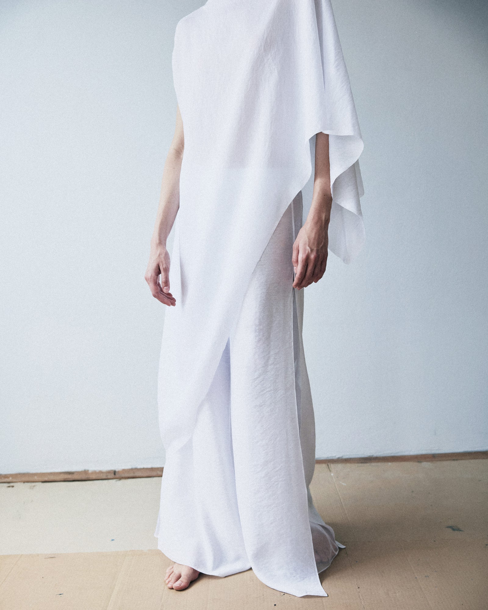 Person wearing a flowing white garment against a plain background
