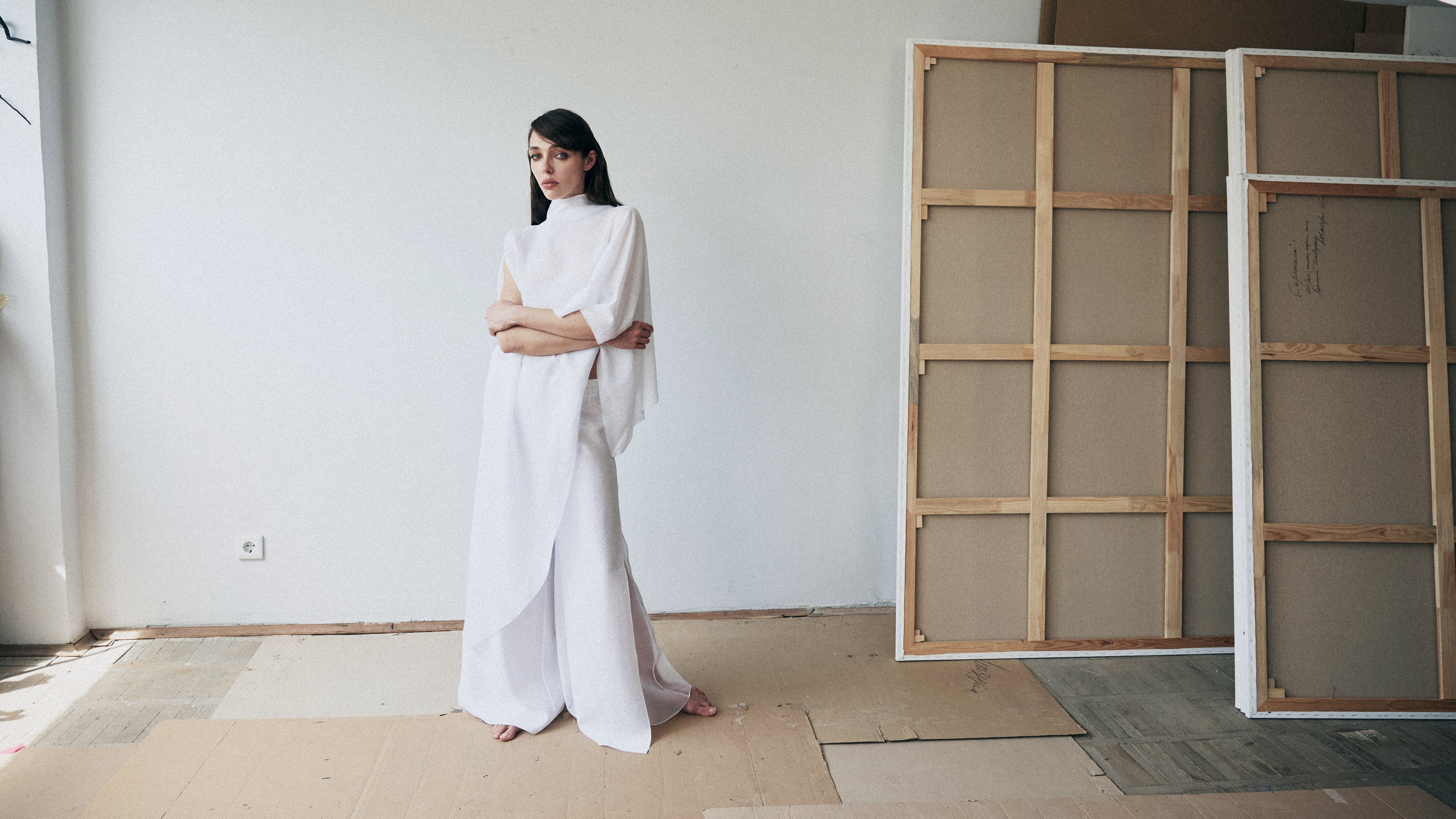 Woman in a white outfit standing in a room with large wooden panels.