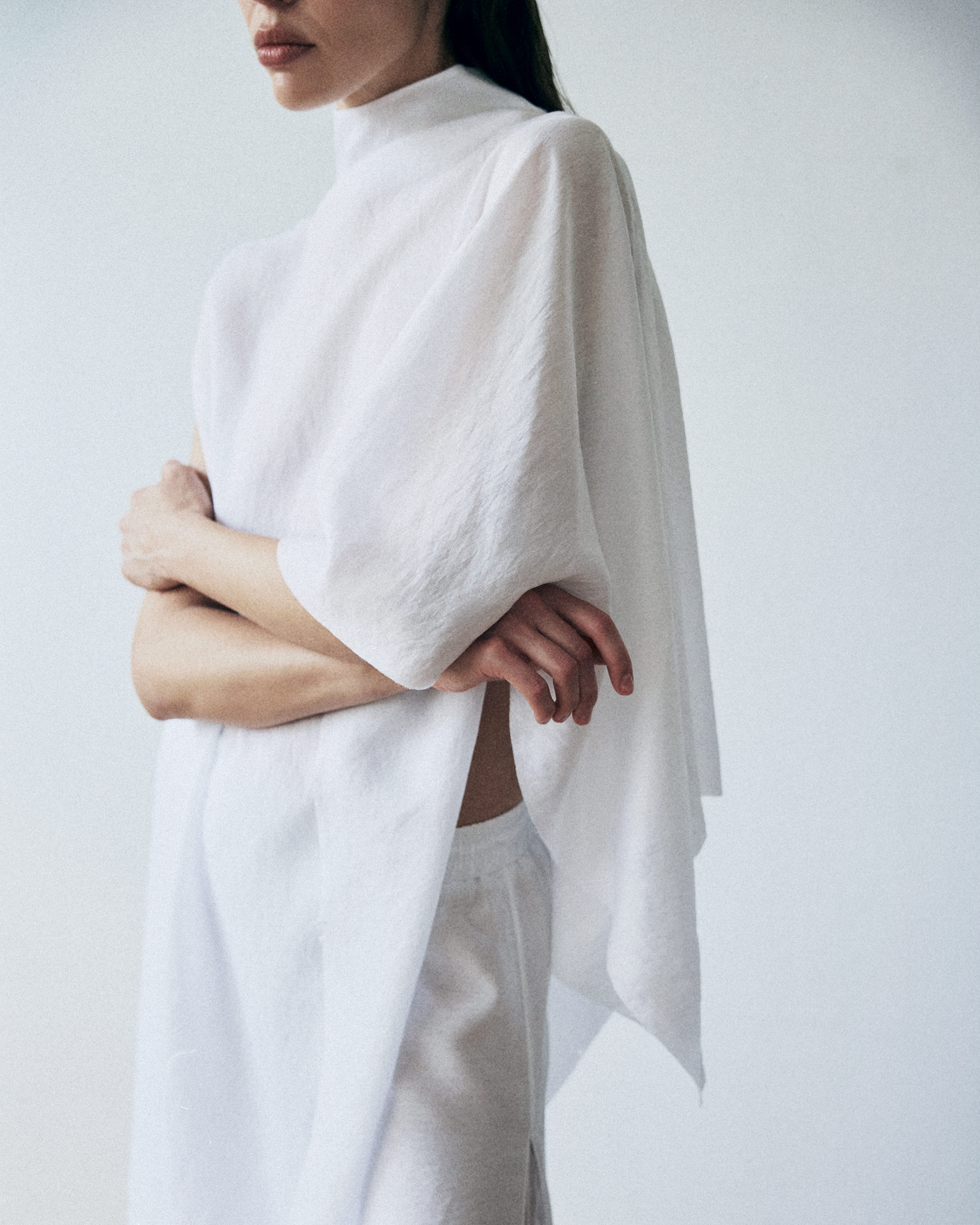 Person wearing a white poncho over a plain background