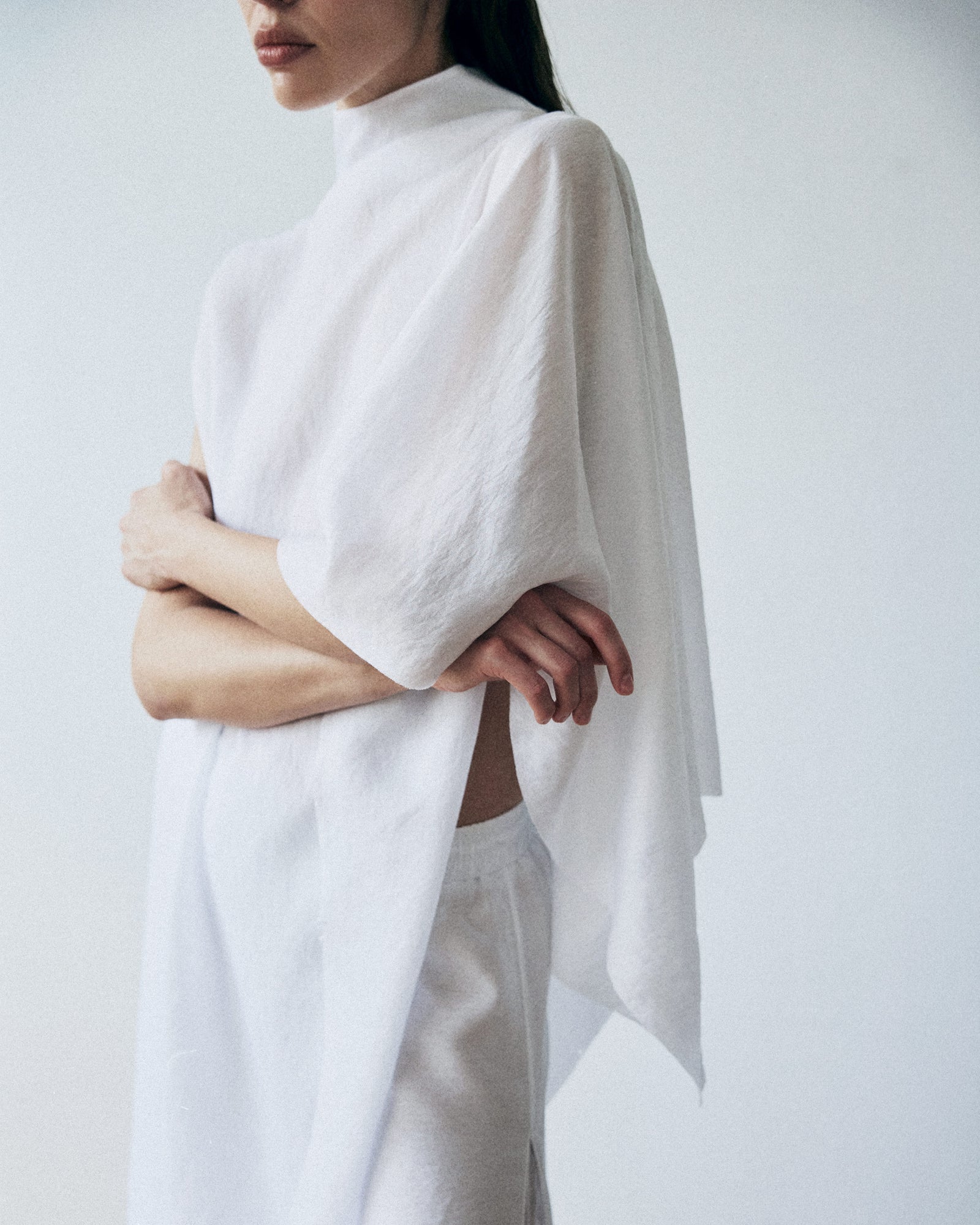 Person wearing a white poncho over a plain background
